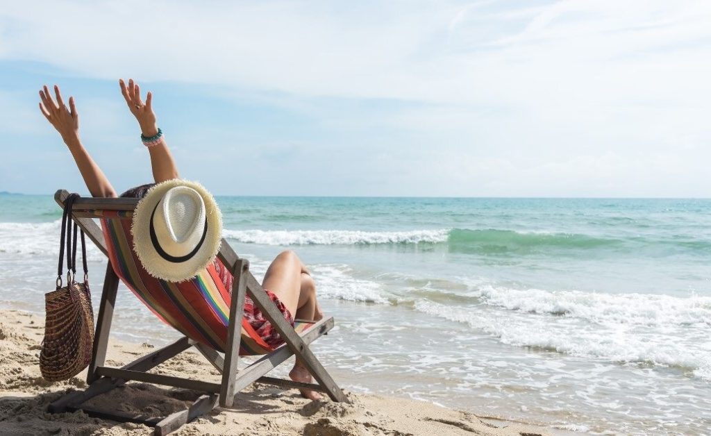 Person relaxing in a beach chair by the ocean.