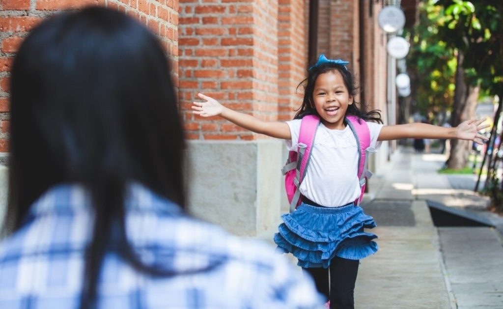 A child running towards an adult with outstretched arms.