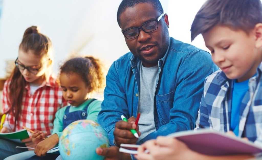Teacher and students looking at a globe and books.