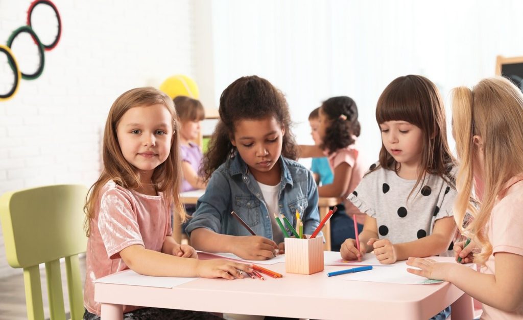 Group of kids doing art activities at desk.