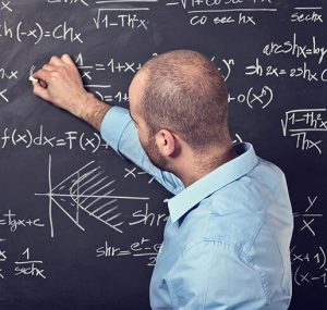 A teacher writing math equations on a chalkboard