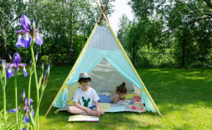 Two children sitting underneath a tent outdoors, reading