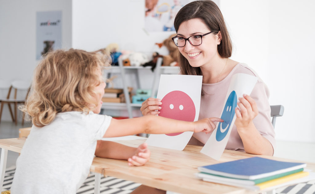 Teacher holding up emotion cue cards for a student to point to