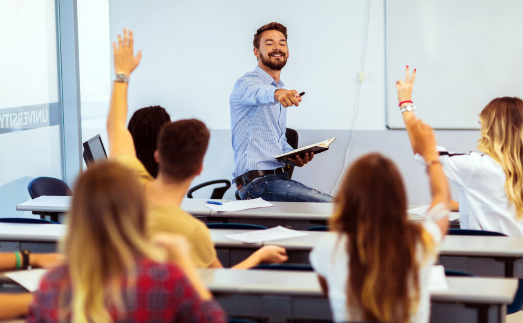 Photo of students raising their hands in a classroom to ask questions