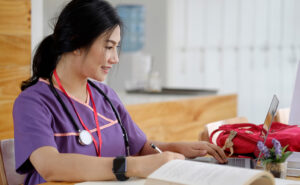 Nurse doing homework with a computer and notebook