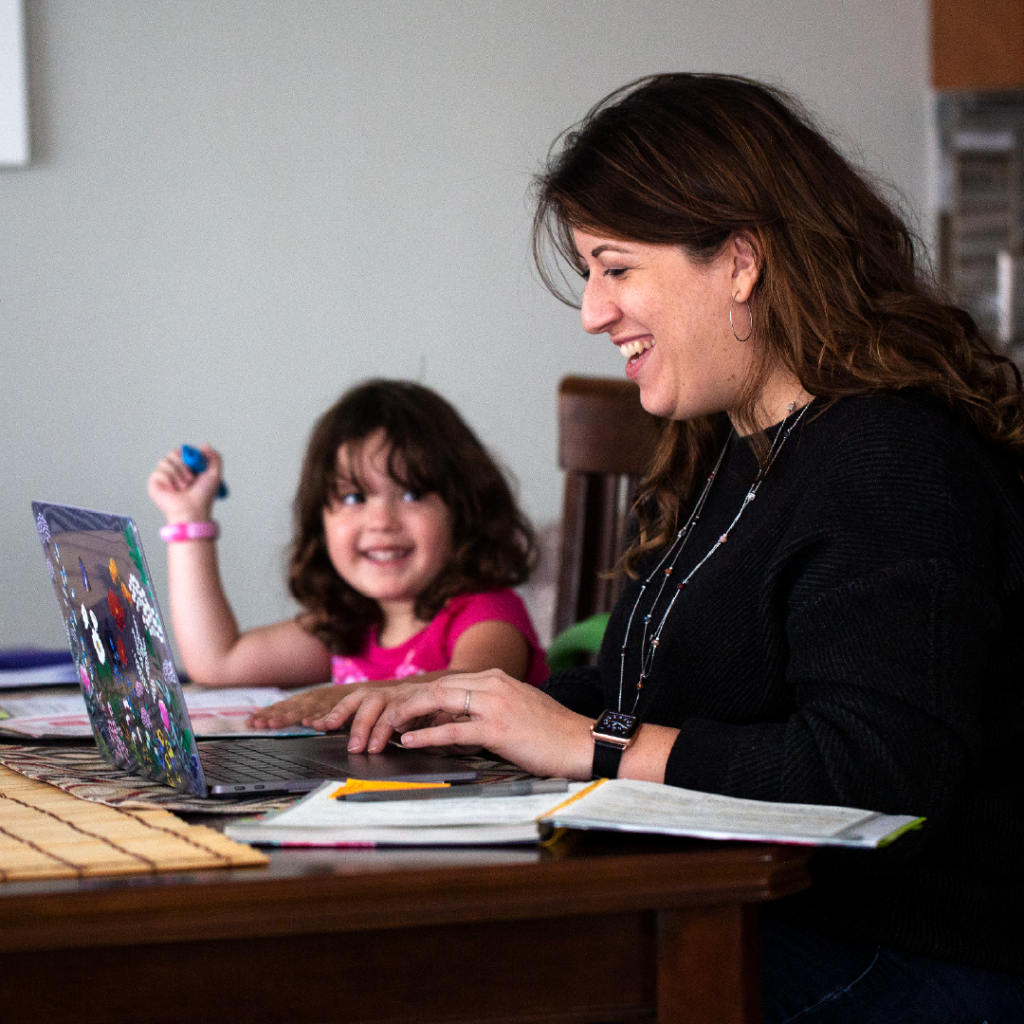 Adult learner completing their online education while at home with their child.