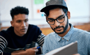 Photo of two young men looking at notebook